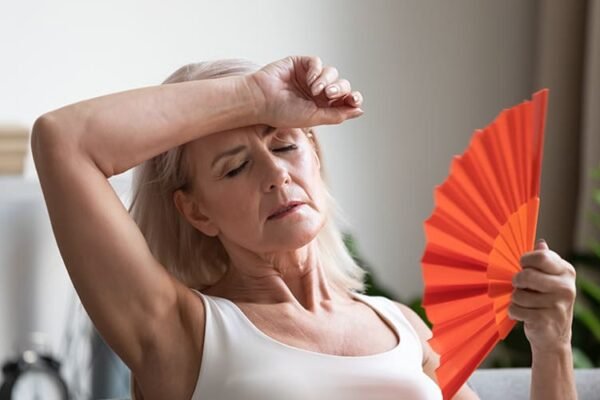 Entenda a Menopausa: Como Aliviar os Sintomas e Desconfortos? Mulher de meia-idade expressando desconforto com os sintomas da menopausa.