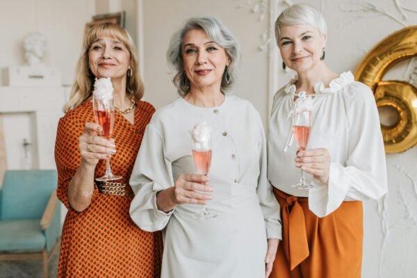 Amora Miura+Vit na Menopausa: Quais os Benefícios? Três senhoras de meia-idade sorrindo enquanto seguram frascos de Amora Miura+Vit, representando os benefícios do suplemento na menopausa para saúde e bem-estar